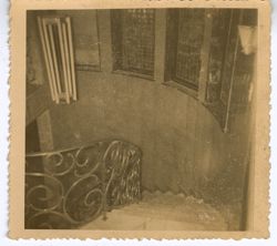 Spiral staircase leading downstairs past windows and chandelier