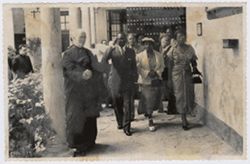 President William V. S. Tubman and Mrs. Tubman walk with priest in courtyard