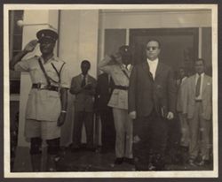 A group of dignitaries and saluting soldiers
