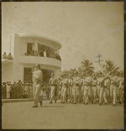 Military men march in parade and salute to crowds in front of Executive Pavilion