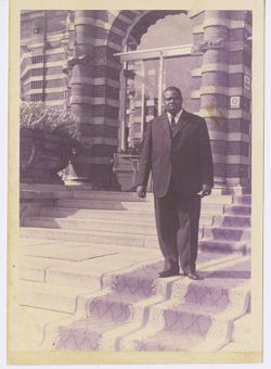 Main in suit stands on steps outdoors