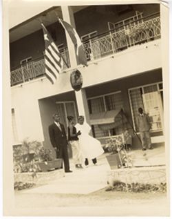 Ambassador C. T. O. King and two others standing under Liberian flag