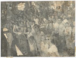 Crowd waves hands and Liberian flags while gathered outdoors