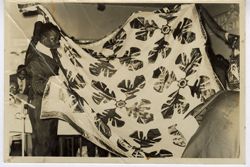 Man unfolds and displays quilt