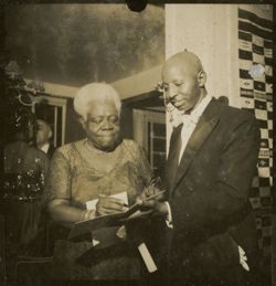 Mary Jane McLeod Bethune, American educator and civil rights leader, signing a document for Liberian Secretary of State Momolu Dukuly, during a 1952 event honoring President Tubman's inauguration