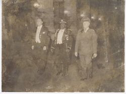 Three officials in formal attire walk down hall