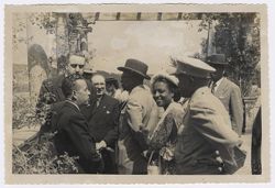 Mrs. Tubman smiles at the camera while President Tubman talks to dignitaries