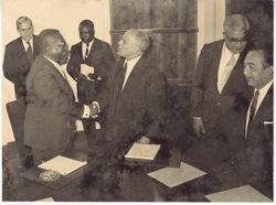 President Tubman shaking hands with man at conference table