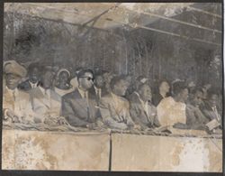 Dignitaries sit in under an awning