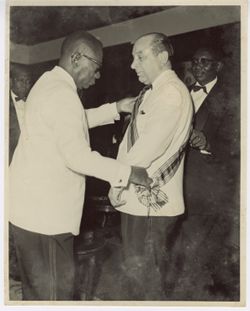 President William V. S. Tubman adjusts ceremonial sash on another