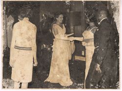 Woman in formal dress shakes hands with party guest