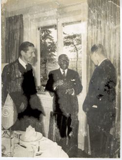 President William V. S. Tubman smiles and stands with two others