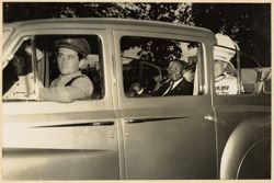 President William V. S. Tubman sits in back of automobile with military personnel during parade