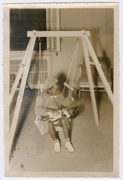 President Tubman's daughter sits on an indoor swing with a doll