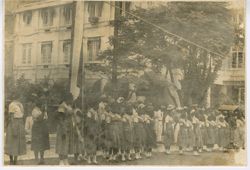 Young girls in uniform line the street during a parade