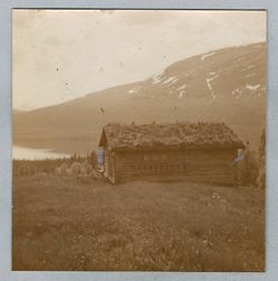 A small cabin on a hill above a lake