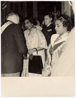 Woman receives a medal and shakes a dignitary's hand