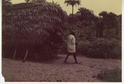 Man walking outside grass house
