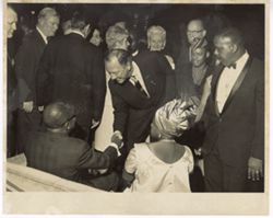 Guest at reception shakes hands with seated man