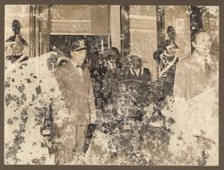 President William V. S. Tubman and Mrs. Tubman walk through a doorway flanked by ornately dressed guards