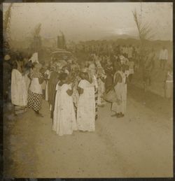 Large crowd gathers around automobiles as they arrive to town