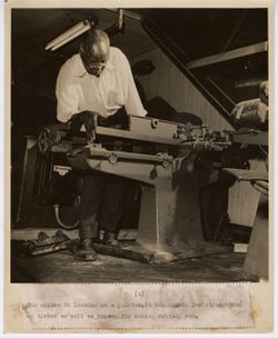 Men leans over jointer machine