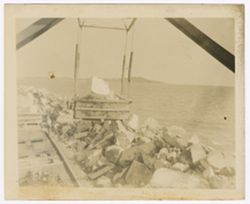Large stone being lifted, workers stand in the background