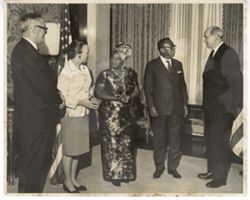 President William V. S. Tubman, U.S. Secretary of State Dean Rusk, Mrs. Tubman and Mrs. Rusk stand in office with American flag in background