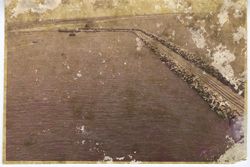 Breakwater with tracks in harbor with boats and shore in distance