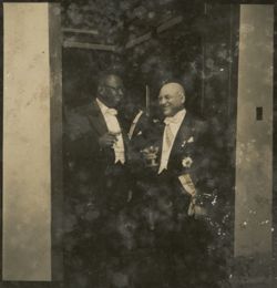 Dressed in formal attire, President Tubman speaks with a dignitary in a doorway