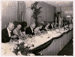 Guests at dinner party sit at long table
