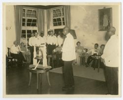 Man standing next to ceremonial bell speaking to guests at reception