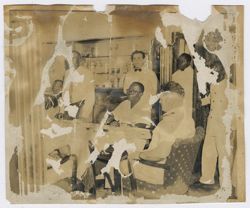 President Tubman seated at the table with guests, waiters stand in the background