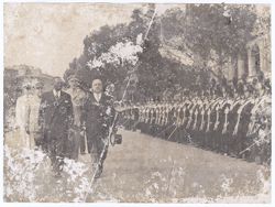 President William V. S. Tubman and others walk together with military men at attention in background