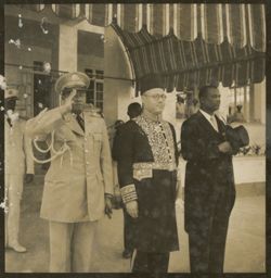 Man in military uniform, man in traditional dress and man in business dress salute