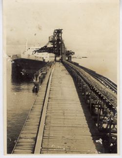 Conveyer belt on dock loads ship in harbor at the Hydroelectirc Plant