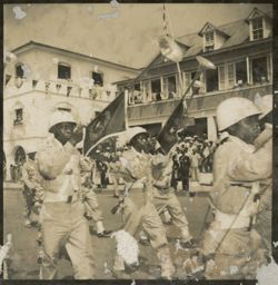 Military men march in parade while carrying ceremonial trumpets