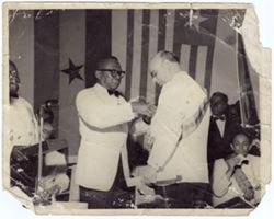 President William V. S. Tubman places a pin on an official's jacket