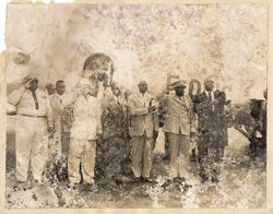 Military officials and men pose in front of airplane on runway