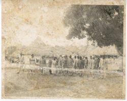 Group of dignitaries and military officials walk through village