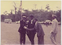 President Tubman in military attire and man in business attire greet one another on airstrip