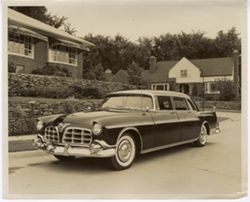 Black car parked on street in front of a house