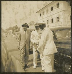 Men stand together outside vehicle