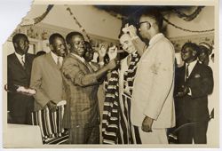 Officials ceremonially clothe fellow dignitary in traditional dress during celebration