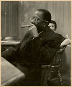 President William V. S. Tubman smoking a cigar at a reception