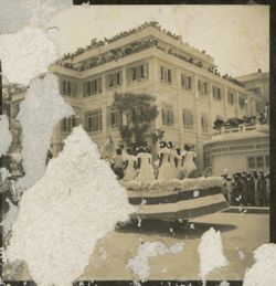 Women in white dresses ride in parade float past crowds in front of Executive Mansion