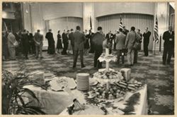 Guests mingle in a large reception room, buffet table in the foreground