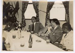 Dignitaries talk while seated at a table with President William V. S. Tubman