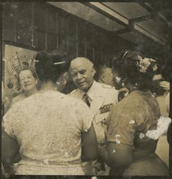 Man in decorated military uniform talks with two women