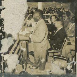 President Tubman speaks to crowd from a balcony surrounded by other dignitaries